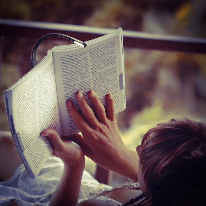 A person reading a book with a white Recharge Light.